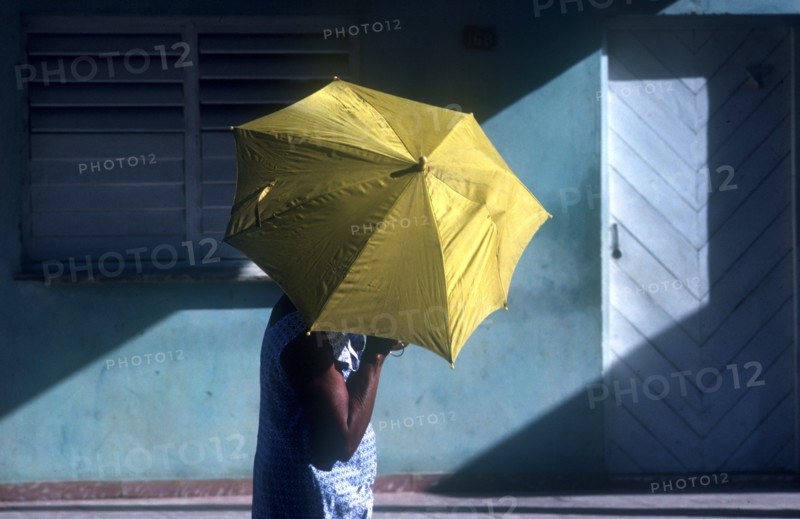 CUBA, Ciego De Avilar  , Woman with yellow umbrella as sun shade in the street