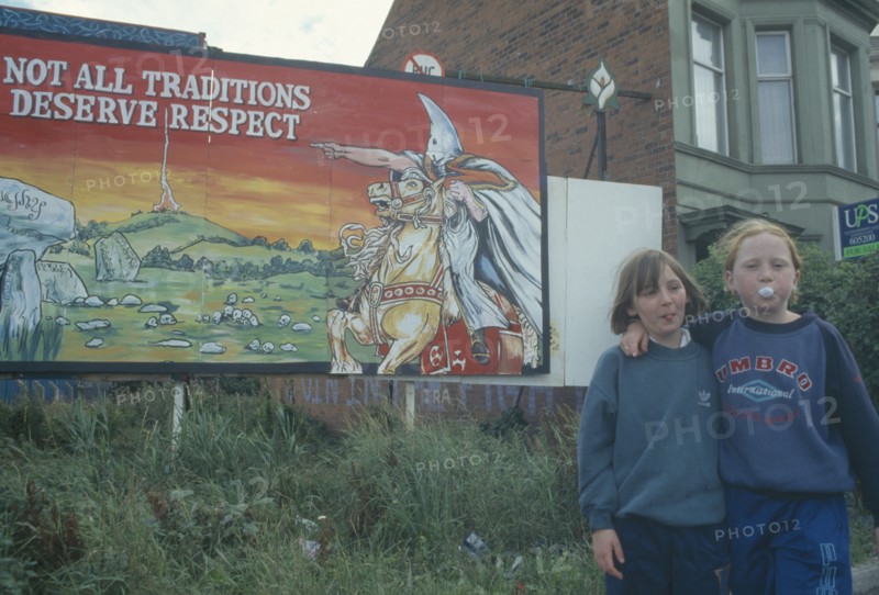 POLITICS, North, Belfast, Nationalist mural with young girls stood next with one girl blowing bubblegum