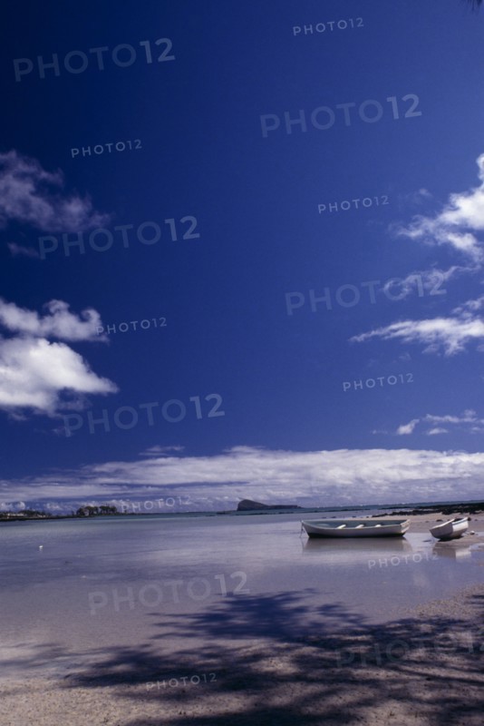 MAURITIUS,  , Grande Gaube, Sandy Beach with moored Boats and an Island in the distance with blue sky and whispy clouds above