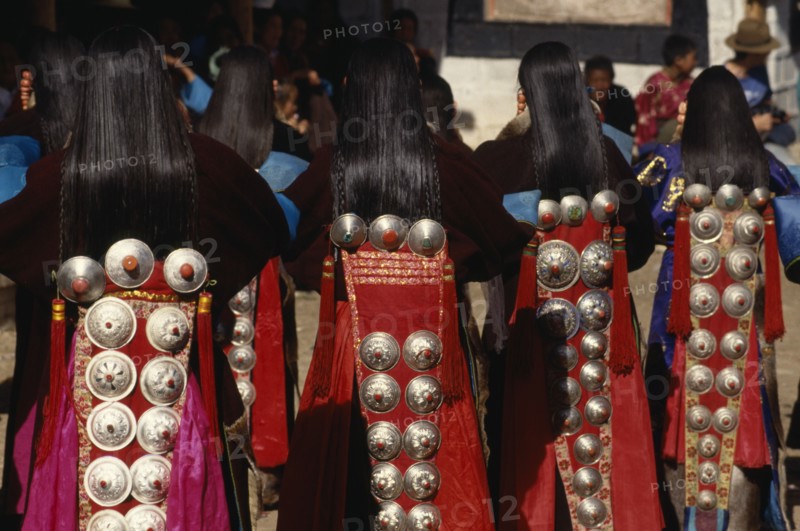 CHINA, Guizhou, Tongren, Tibetan dancers at a festival wearing traditional costumes with silver ornamental designs