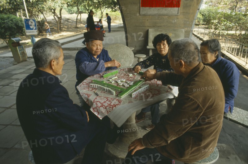 CHINA, Guangzhou,  Men and women sat around table playing Mahjong