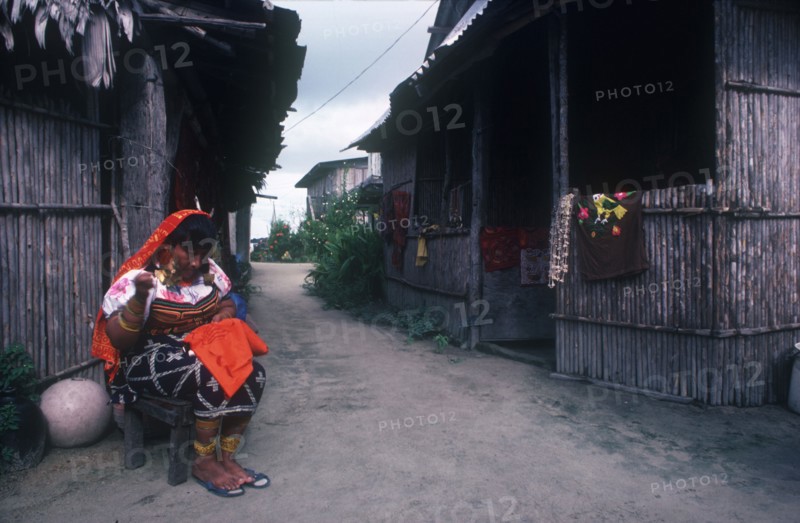 PANAMA,  , San Blas Islands, Cuna Indian woman sitting outside huts working on embroidery