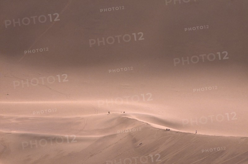 CHINA, Gansu, Dunhuang, Sand dunes with people standing on the ridge in the distance