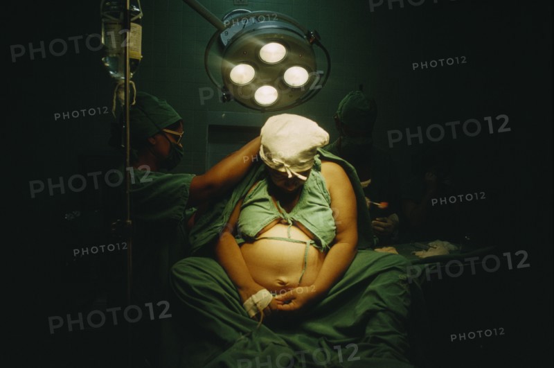 CUBA, Havana, Woman in labour sitting on an operating table with doctors at her sides