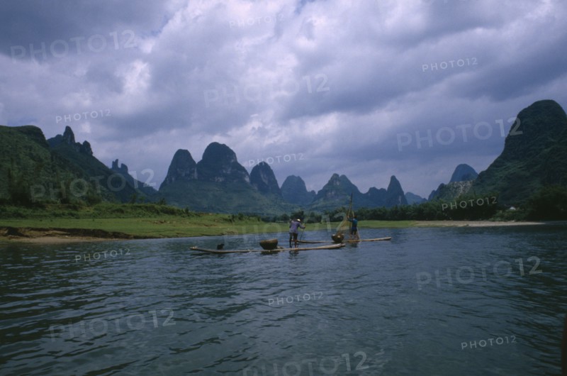 CHINA, Guangxi, Guilin, Cormorant fishermen on rafts on the River Li with limestone karst mountains in the distance