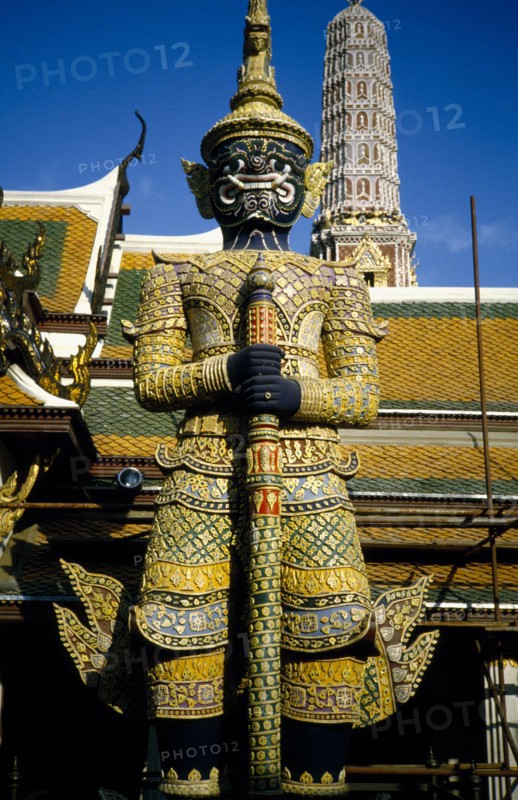 THAILAND, Bangkok, Wat Phra Kaew, Or Grand Palace. Elaborate statue with tower behind