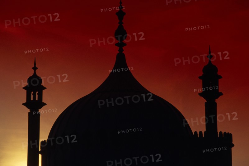 ENGLAND, East Sussex, Brighton, The Royal Pavilion. Detail of domes silhouetted at sunset with a red sky