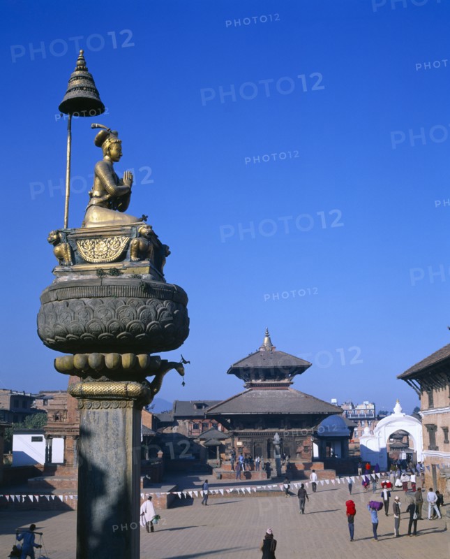 NEPAL, Bhaktapur, Main square with temple and gold statue on tall plinth.