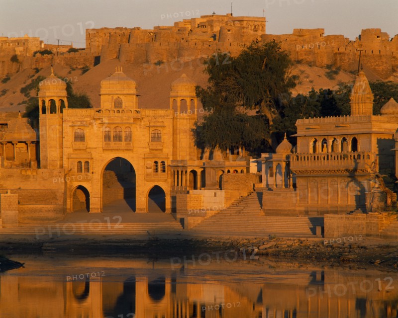 INDIA, Rajasthan, Jaisalmer, Gadi Sagar Tank  with buildings the Fort in the background