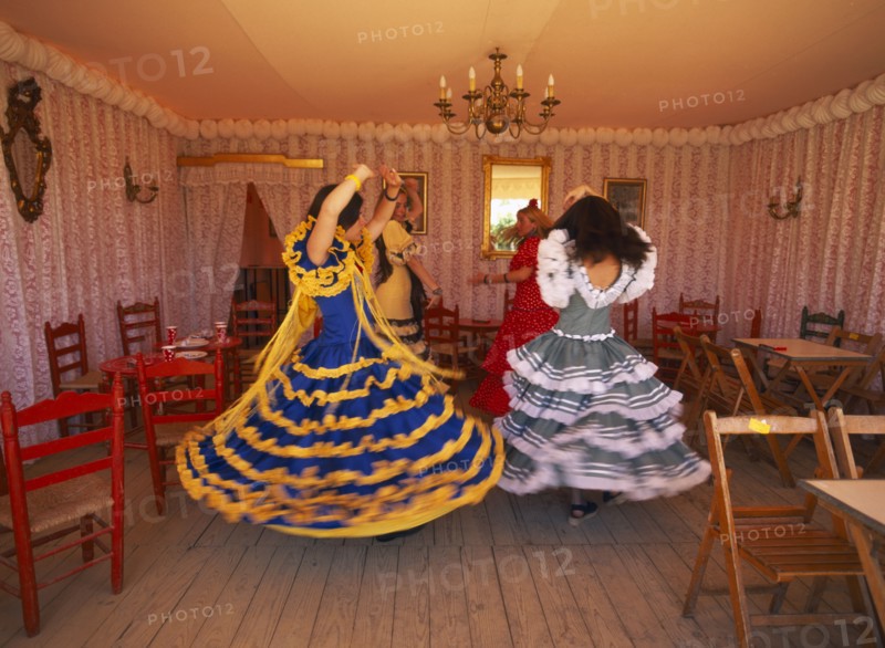 SPAIN, Andalucia , Seville, Three young girls in Flamenco dresses dancing in one of the tents at the April Fair