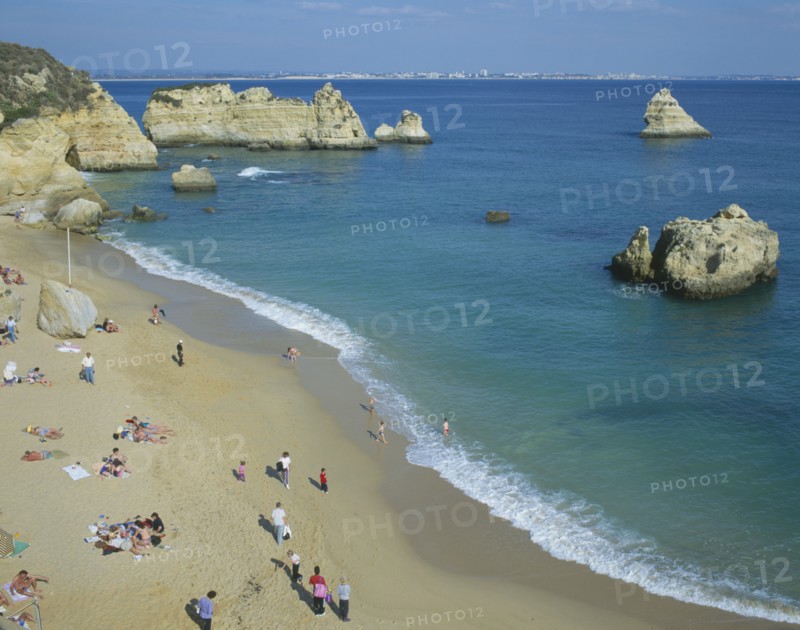 PORTUGAL, Algarve, Lagos, "Sandy beach, outcrops of rocks in sea, family groups "