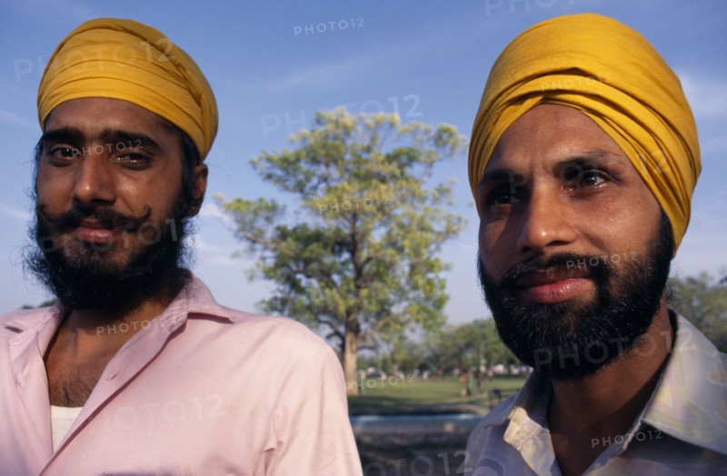 INDIA, Delhi , "Two Sikh men, head and shoulders portrait wearing orange turbans."