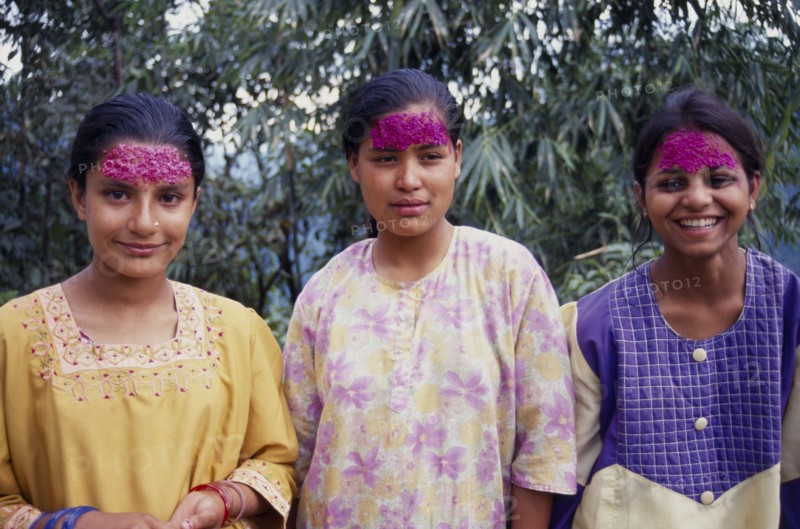 INDIA, Sikkim , Tashiding, Three young women with coloured rice on their foreheads for Diwali.  Three-quarter portrait.