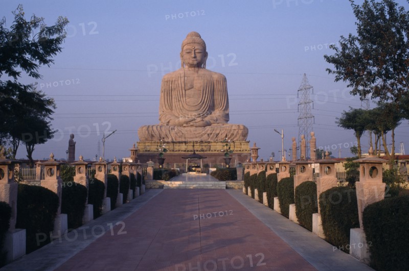 INDIA, Bihar, Bodh Gaya, Giant seated Buddha statue seen from pathway leading up to the base.