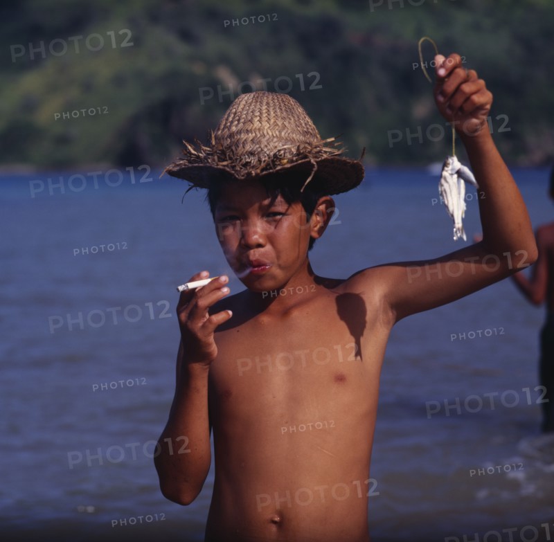 INDONESIA, Lombok, Mawon, "Boy smoking cigarette, hat, small fish on line "