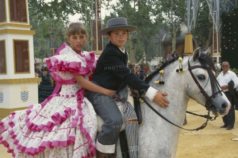 SPAIN, Andalucia, Jeréz de la Frontera, Children in flamenco costume on a grey pony at Jerez horse fair.