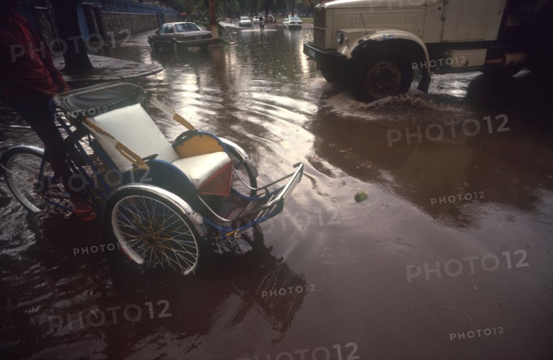 CAMBODIA, Phnom Penh, "Street near the Royal Hotel flooded after the monsoon rains.  Car, truck and rickshaw surrounded by water."