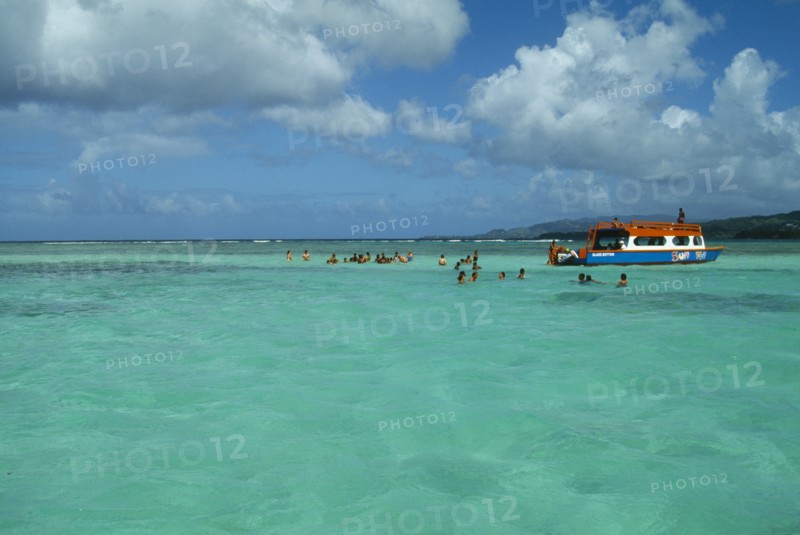 WEST INDIES, Tobago, Buccoo Reef, The Nylon Pool with tourists swimming or standing in shallow water by boat