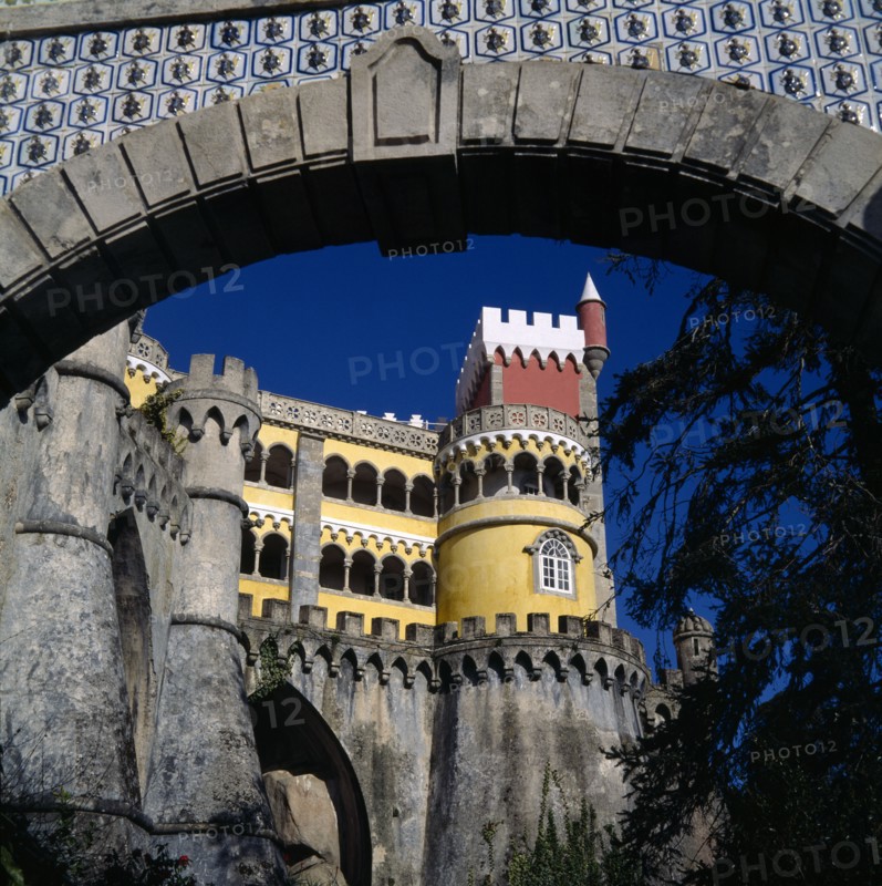 PORTUGAL, Estremadura, Sintra, Pena Palace. View through archway to yellow and red tower with arches and crennalations