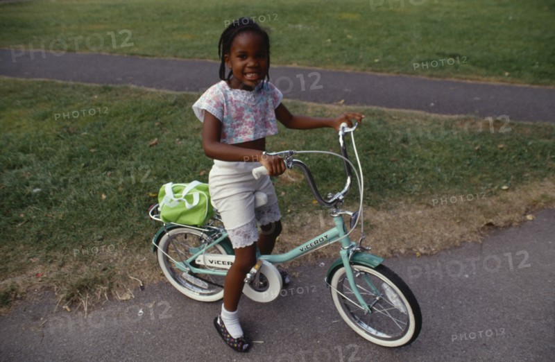 10037908 ENGLAND  London Young black girl on bicycle on Clapham Common.