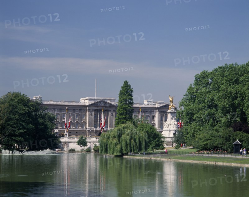 ENGLAND, London, Buckingham Palace. View from Green Park with trees surrounding lake and fountains