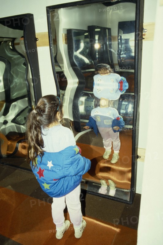 ENTERTAINMENT, Fairground, Crazy Mirrors, Young girl looking at her own distorted reflection in crazy mirror.