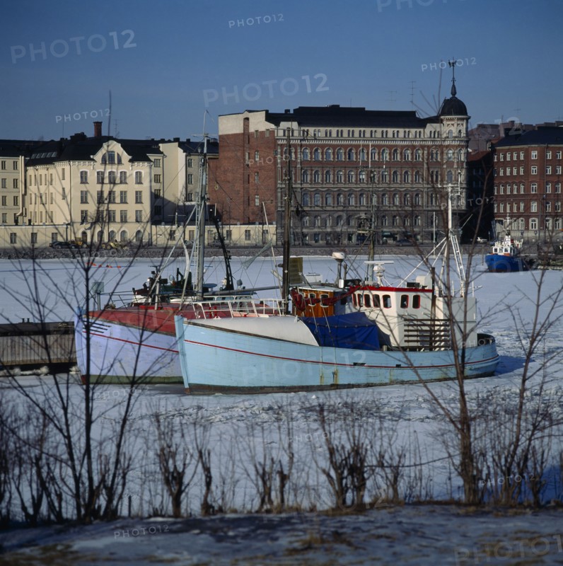 FINLAND, Uusimaa, Helsinki, "North Harbour,fishing boats,frozen sea,buildings beyond "