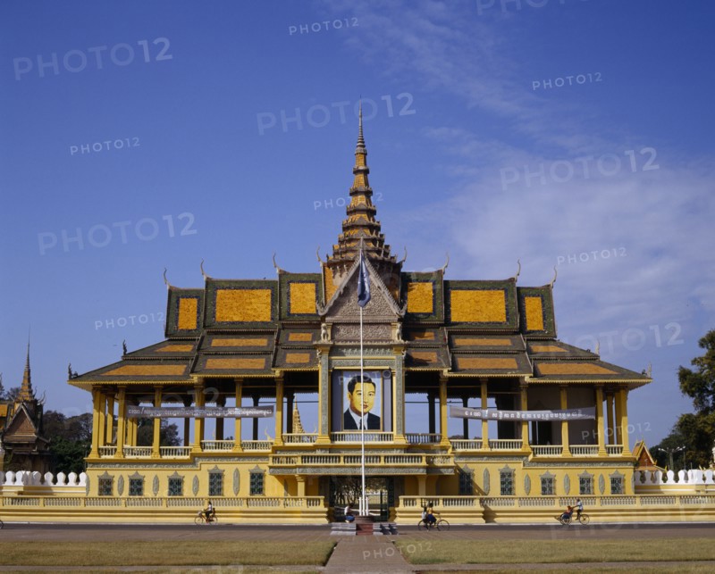 CAMBODIA, Phnom Penh, The Royal Palace.  Exterior and entrance gate with passing cyclists.