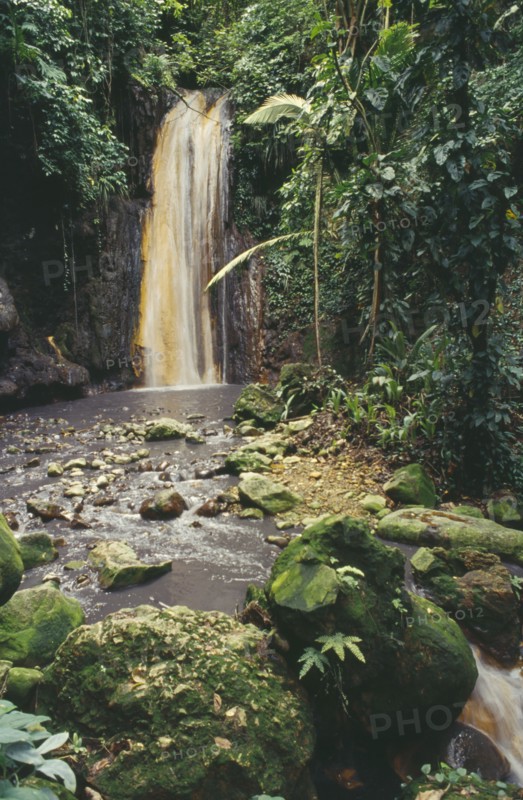 WEST INDIES, St.Lucia , Soufriere, Diamond Waterfalls falling into river bed lined with lush green foliage