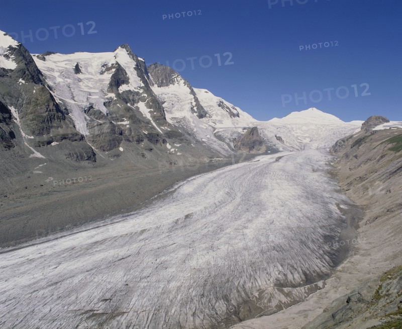 AUSTRIA, Karnten, Pasterze Glacier, View looking up glacier showing lateral moraine and mountainous sides with a blue sky above