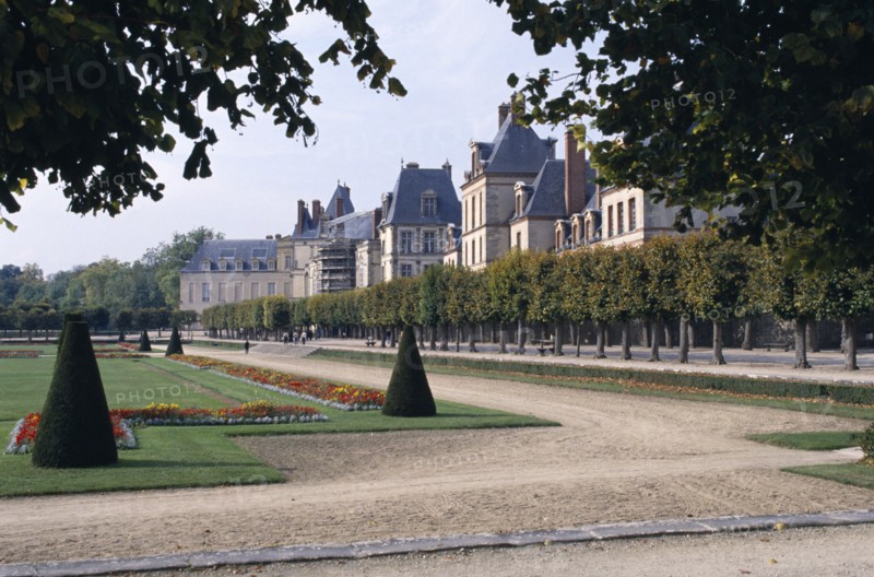 FRANCE, Fontainebleau, Palace and gardens framed by tree branches