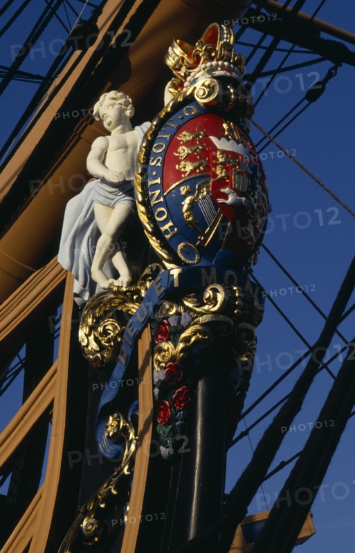 ENGLAND, Hampshire, Portsmouth, Admiral Lord Nelson's HMS Victory. Detail of elaborate figurehead of two cupids supporting the royal coat of arms and royal crown. The arms bear the Norman French inscription of the Order of the Garter Honi Soit Qui Mal Y Pense which means-shame to him who evil thinks