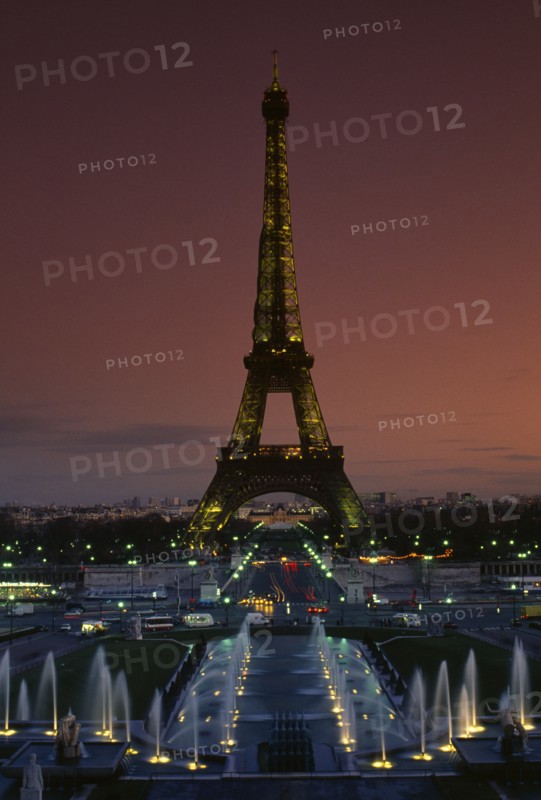 FRANCE, Ile De France, Paris, Eiffel Tower illuminated at dusk with illuminated fountains in the foreground