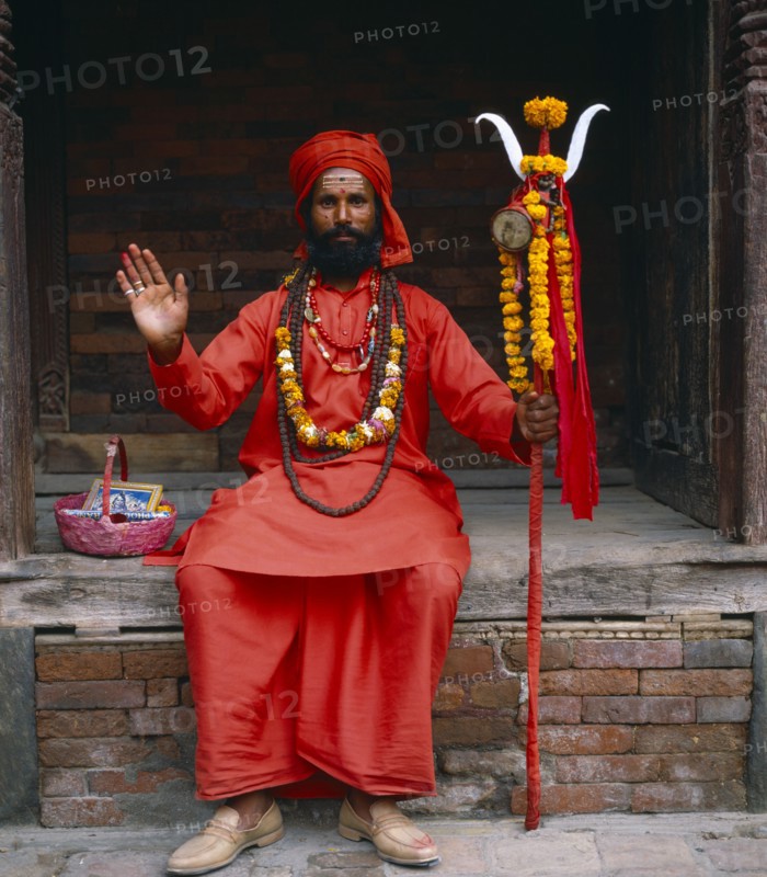 NEPAL, Kathmandu, Full length portrait of holy Man dressed in red.