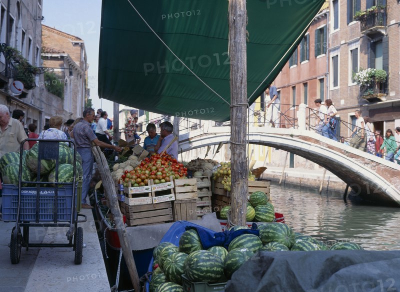 ITALY, Veneto, Venice, Fruit and vegetable stall on a boat on the riverbank near a small bridge
