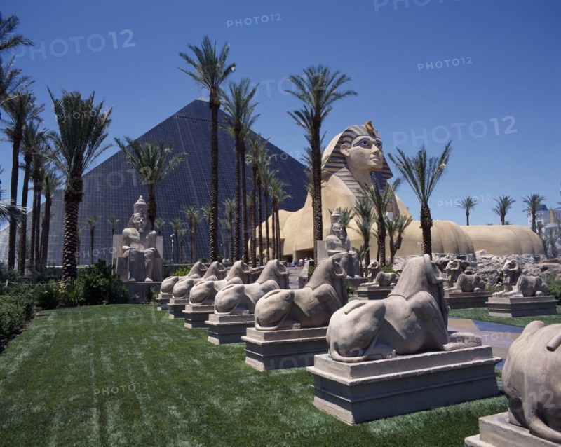 USA, Nevada, Las Vegas, Luxor Hotel and Casino Pyramid shaped building with Sphinx and row of stone rams on lawns beside a palm lined avenue