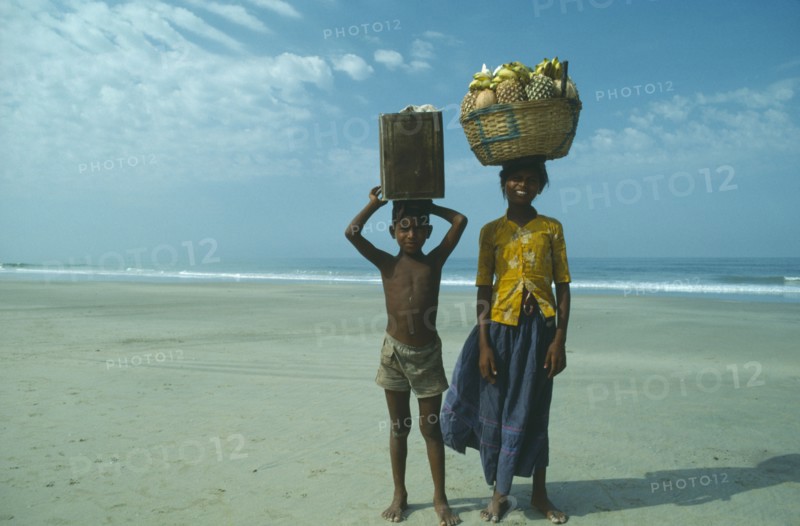 INDIA, Goa, Colva, Boy and girl from Karnataka on beach carrying fruit and drinks to sell to tourists