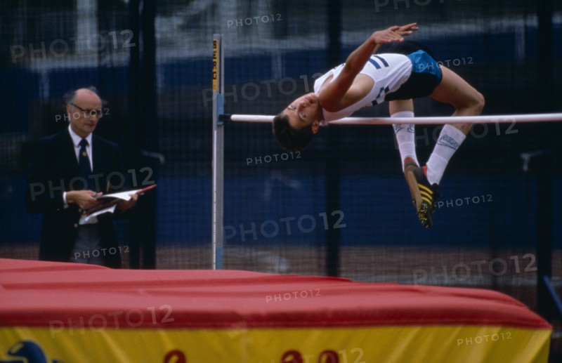 10000115 SPORT Athletics High Jump Competitor in junior athletics championships clearing bar in high jump.