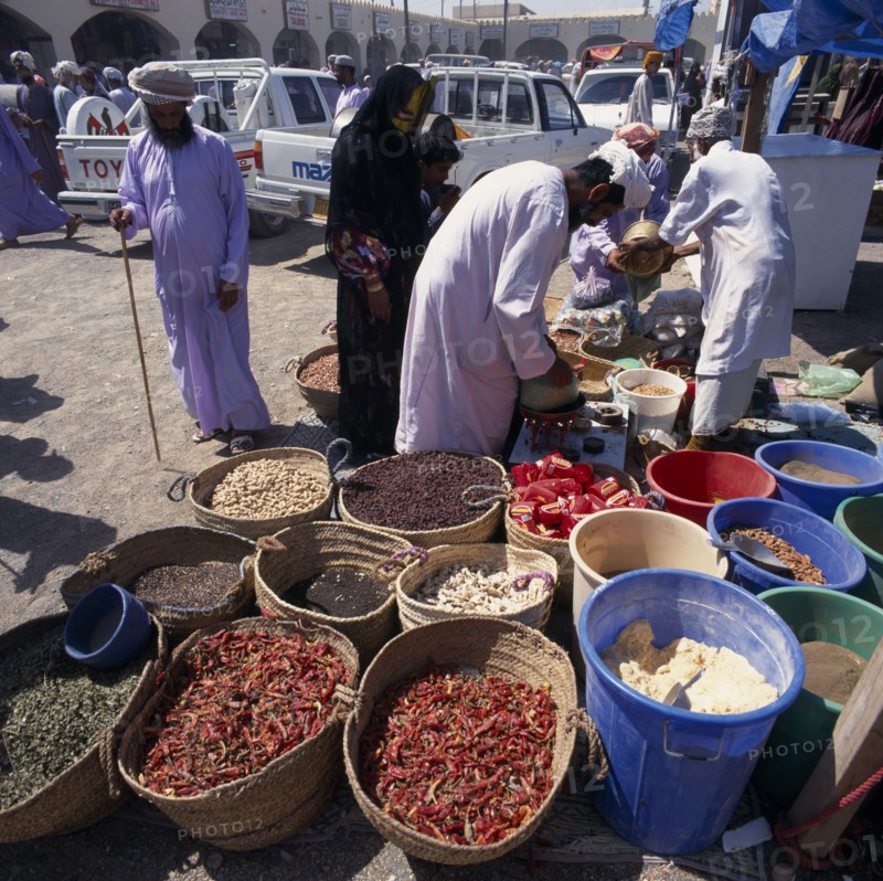 OMAN, Sharqiya, Sanaw, Local people in souk spice stall with spices in baskets and in bins.