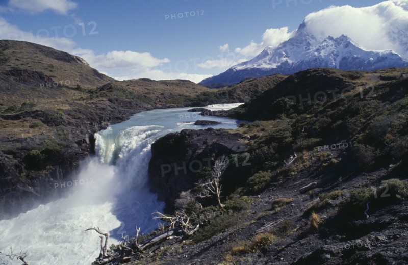 CHILE, Torres Del Paine , Great Falls in the National Park. White water plunging over cliff edge with snowcapped mountain peaks in the distance