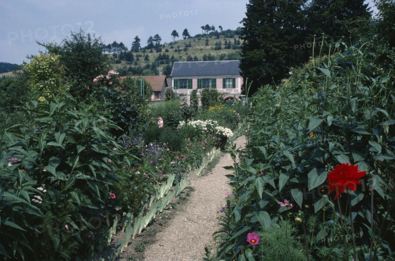 FRANCE, Normandy, Giverny, A path leading through Claude Monet’s garden towards a house.