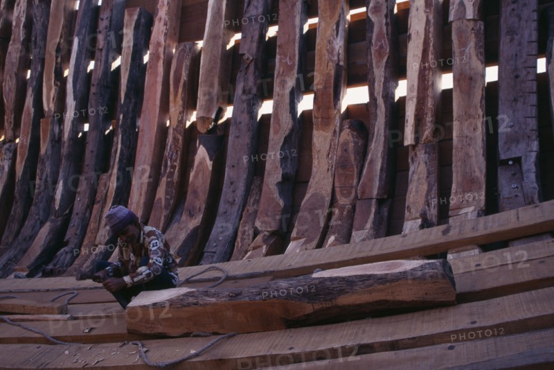 INDIA, Gujarat, Veraval, Shipbuilding.  Man working on interior shell of boat.
