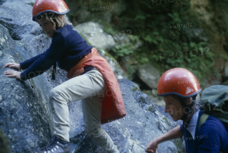 10127733 SPORT  Climbing Woman and child rock climbing wearing red safety helmets in North Wales