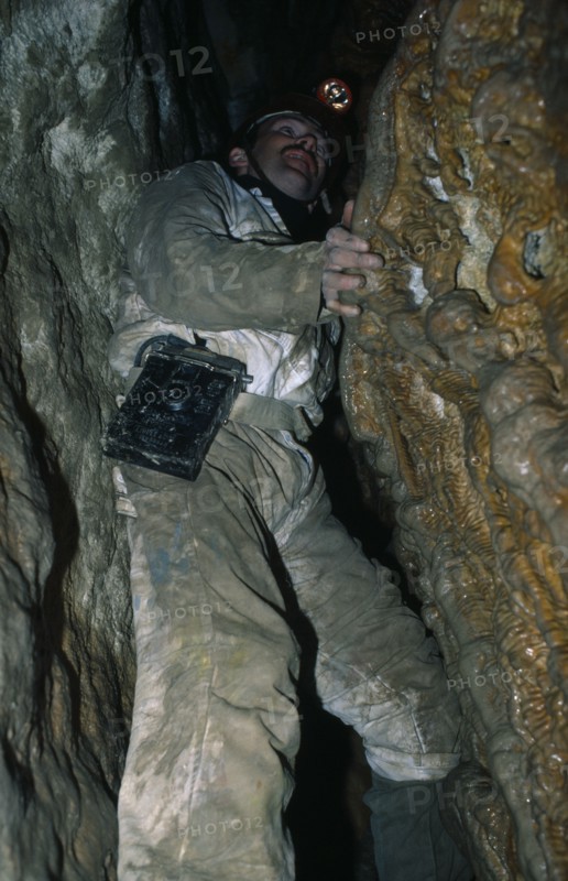 10009982 SPORT Rock Climbing Caving Man climbing in Limestone Area with spotlight on his head.
