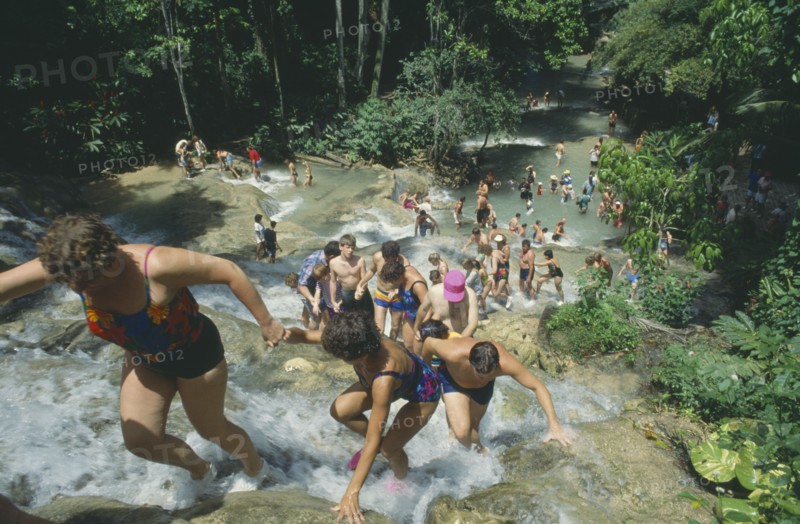 WEST INDIES, Jamaica, Ocho Rios, Tourists helping each other up to the top of Dunns River Falls