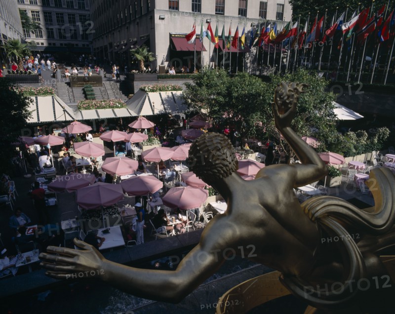 USA , New York State, New York, "Rockefeller Centre, open air cafe with pink umbrellas and gold statue in the foreground"