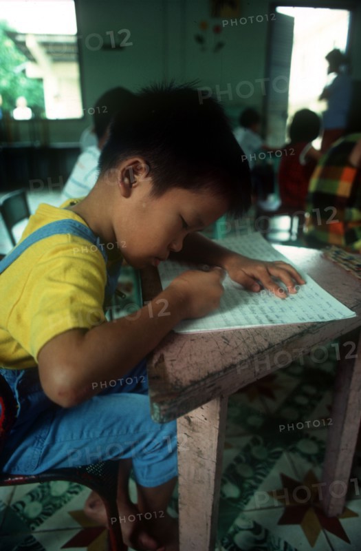 VIETNAM, Ho Chi Minh City, Child writing at a desk in an Agent Orange Orphanage.