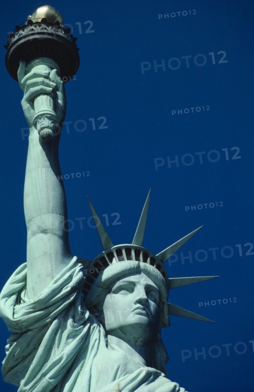 USA, New York State, New York, Statue of Liberty. Close up view of the head and raised arm against blue sky