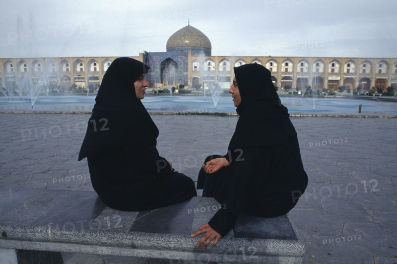 IRAN,  , Esfahan, Emam Khomeini Square Two women talking Sheikh Lot Fallah mosque in background  Isfahan