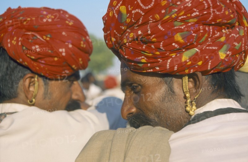 INDIA, Rajasthan, Nagur, Two men wearing turbans and earrings with backs to camera